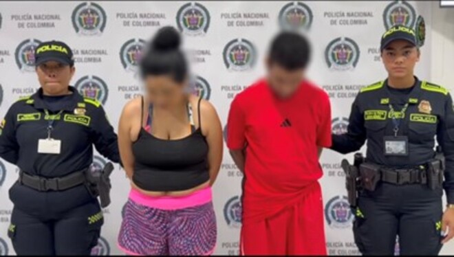 Dos personas detenidas posan junto a agentes de la Policía Nacional, frente al fondo oficial de la institución