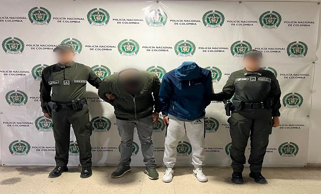Dos policías al lado de dos presuntos delincuentes sindicados de hurto 