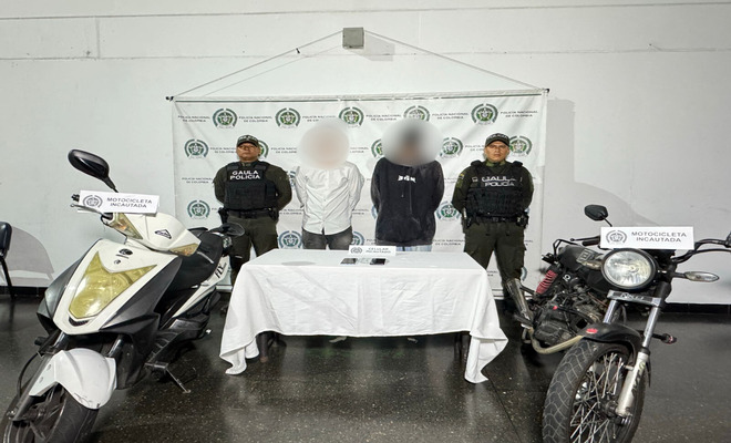Dentro de un salón, la Policía Nacional presenta a dos hombres con sus rostros difuminados como presuntos responsables de un caso de extorsión. En el lugar también se muestran dos motocicletas y varios teléfonos celulares que fueron incautados durante el operativo