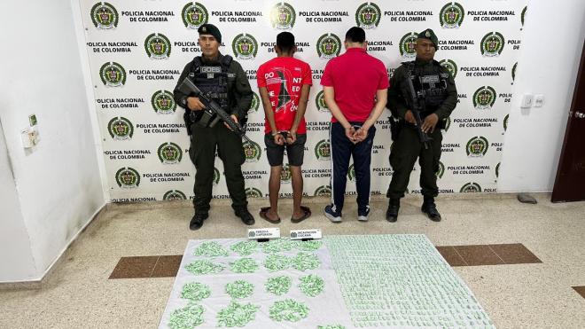 Dos hombres de camiseta roja capturados en medio de dos policías