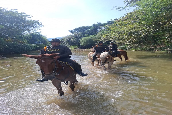 Tres Policías de carabineros en sus caballos pasando el rio 