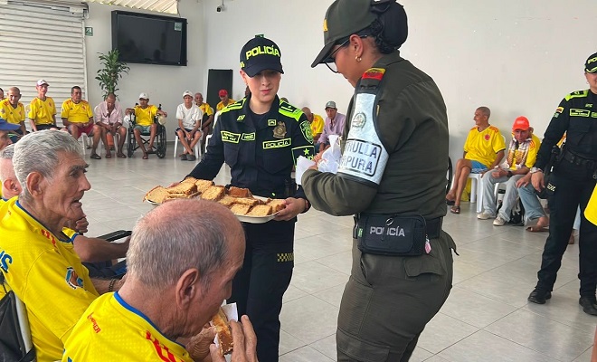 Dos funcionarias de la Policía Nacional brindando un compartir a los adultos mayores 
