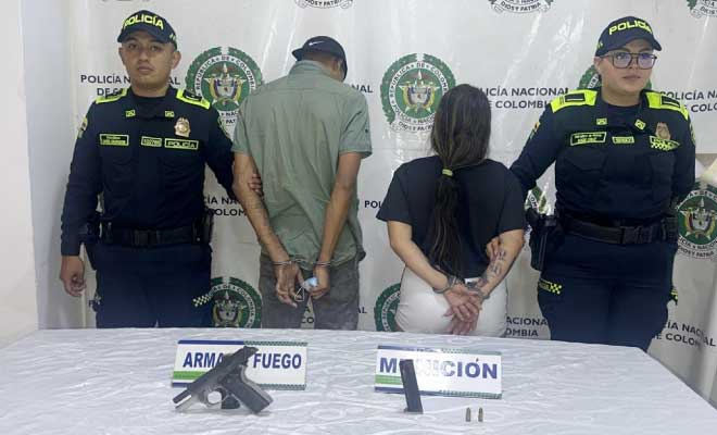 Hombre y mujer capturados en media de dos policías, en frente arma de fuego incautada