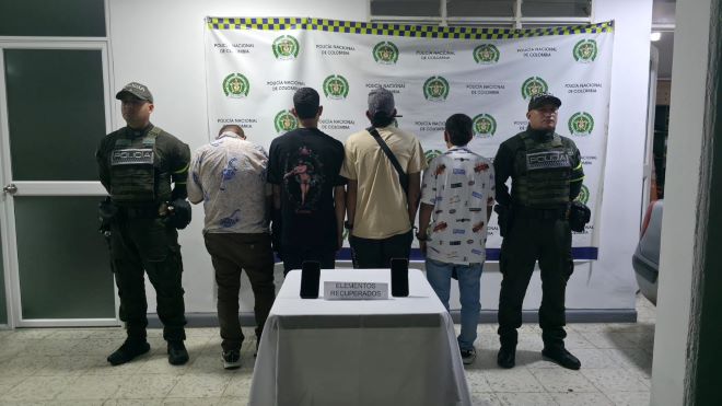 Dos policías al lado de cuatro hombres capturados