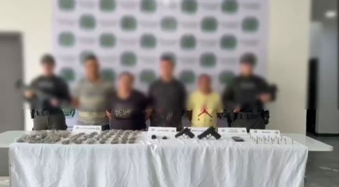 dos policías al lado de cuatro capturados con material incautado