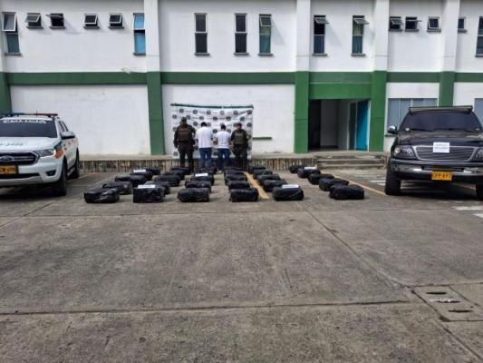 Dos policías al lado de dos hombres capturados