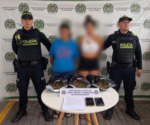 dos policías al lado de dos mujeres capturadas con estupefacientes