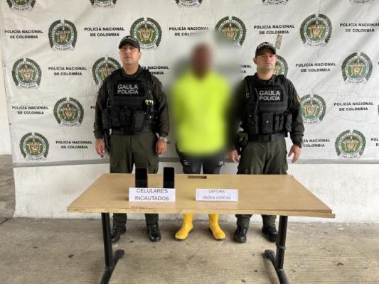 Dos policías al lado de un hombre capturado