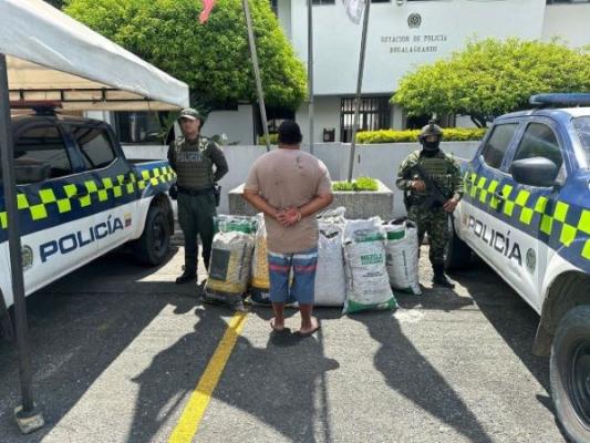 Dos policías al lado de un hombre capturado con carbón 