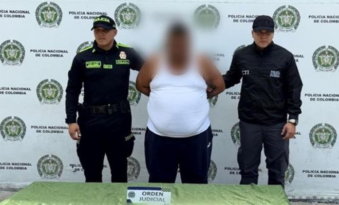 Dos policías al lado de un hombre capturado por orden judicial 