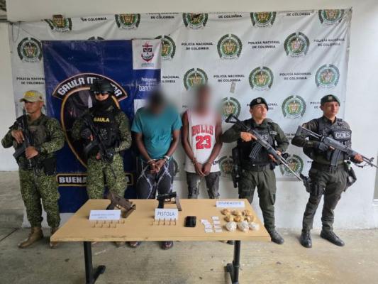 Dos policías al lado del ejercito con dos capturados y elementos incautados.