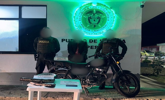 De noche, dos polic&iacute;as junto a una mesa con los elementos incautados, una moto y la persona capturada 