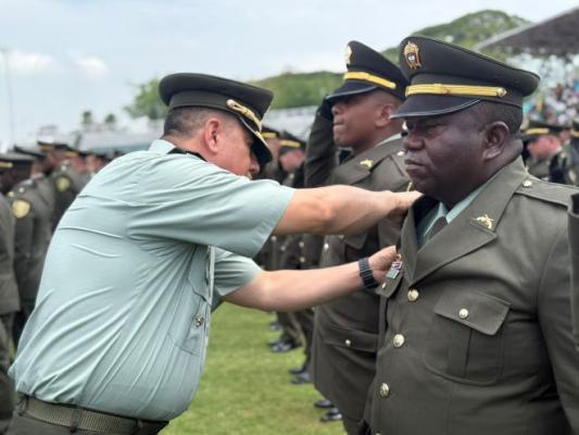 el señor coronel al lado de un policía colocando la insignia