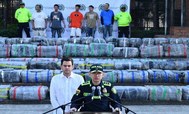 En un escenario al exterior la Policía Nacional de Colombia vocero junto al secretario de seguridad de la  Alcaldía, detrás presentan la incautación de marihuana envuelta en plásticos.