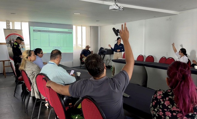 Uniformado del grupo de Turismo de la Policía Nacional en compañía de dos funcionarios de Migración Colombia y seis ciudadanos integrantes del gremio hotelero sentados en mesa redonda realizando participación activa en la actividad