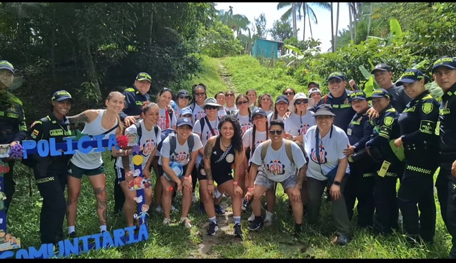 Una amplia agrupación de personas se posa en un entorno con vegetación al fondo, mezclando deportistas y miembros de la fuerza policial. Todos están juntos, formando un solo grupo en una foto colectiva que une al equipo deportivo con la institución policial, mostrando una relación de colaboración o evento conjunto