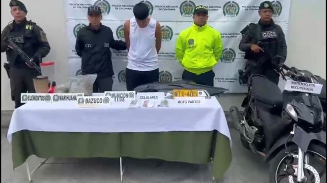 la policía nacional CTI al lado de un hombre capturado con material incautado