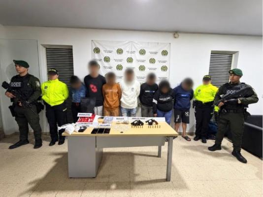 la policía nacional al lado de siete hombres capturados con celulares, estupefacientes y armas de fuego