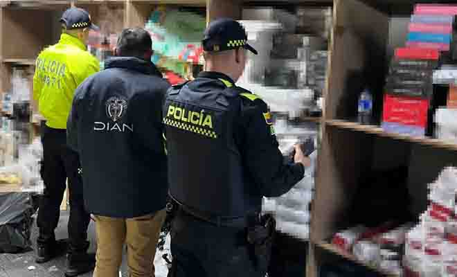 Dos policías y un funcionario DIAN revisando artículos tecnológicos