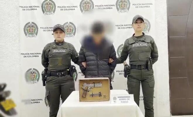 Una persona capturada esposada con un arma de fuego incautada 