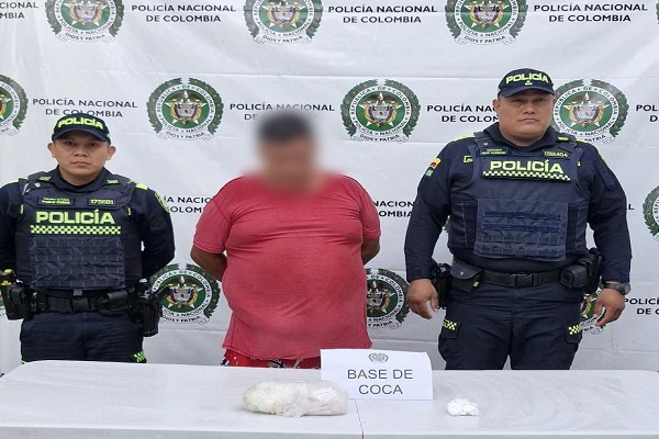 Dos policías junto a un hombre capturado y sustancia estupefaciente incautada