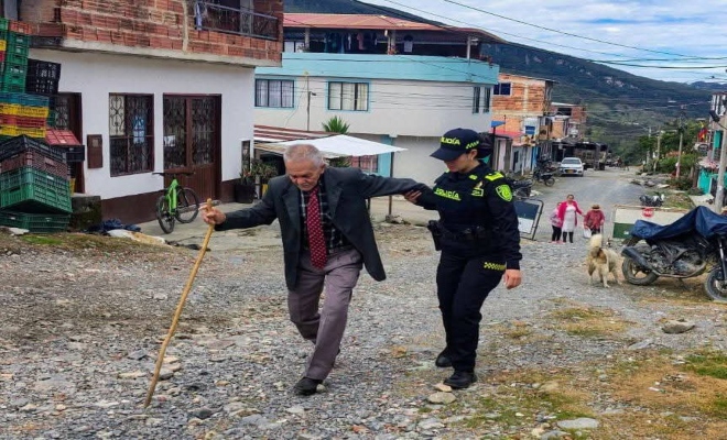 un policía en horas de la mañana ayudando a un señor a que llegue a su punto de votación y pueda ejercer su derecho al voto