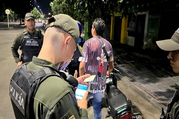 Policía realizando solicitud de antecedentes a un ciudadano y otro Policía prestando la seguridad