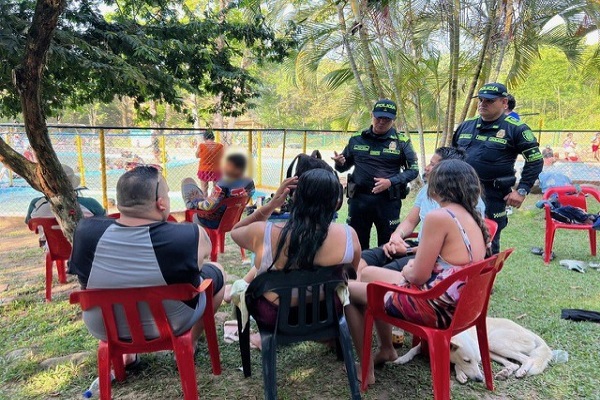 Dos Policías del Grupo de Protección al Turismo y Patrimonio brindando recomendaciones especiales a cuatro ciudadanos para garantizar la integridad de los usuarios