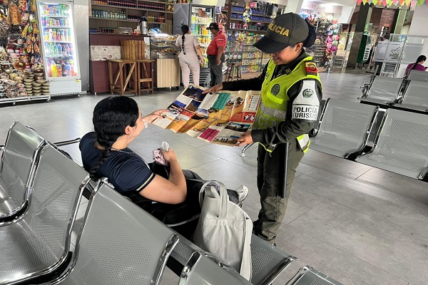 Polic&iacute;a de turismo realizando socializaci&oacute;n a una ciudadana en el terminal de transporte