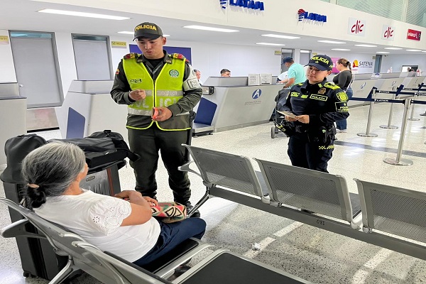 Dos Policías de turismo realizando campaña preventiva con una ciudadana en el aeropuerto