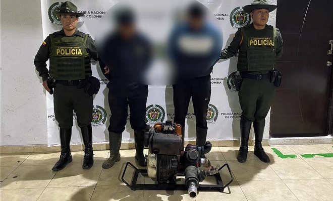 Dos ciudadanos capturados por extracción ilegal de recursos hídricos , esposados con dos policías de Carabineros en cada lado respectivamente 