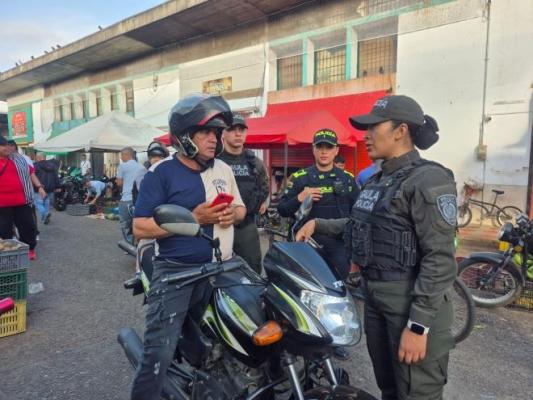 Tres policías al lado de un ciudadano en una motocicleta 