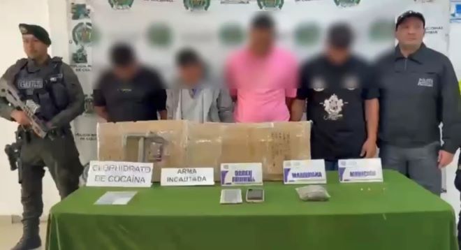 un policía al lado de cuatro capturados y un funcionario del CTI