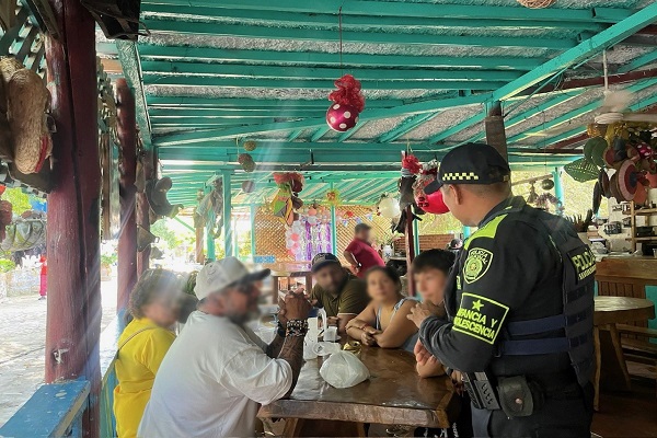 Policía de infancia y adolescencia compartiendo recomendaciones a cinco ciudadanos referente al cuidado de los menores de edad 
